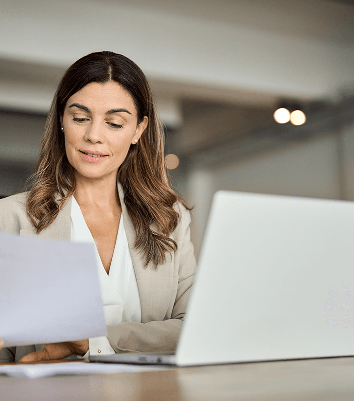 Professional reviewing documents at a laptop